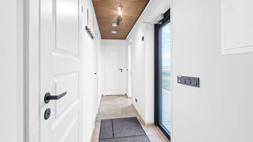A modern hallway with white doors, a wooden ceiling, and a view through a glass door.