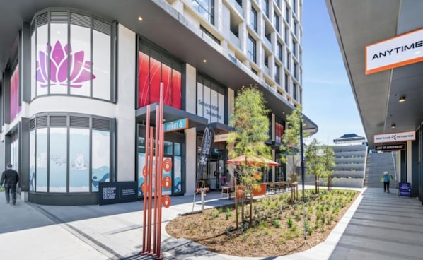 A modern building with a large lotus flower logo, a service entrance, and a seating area with a garden.