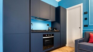 A compact kitchen with dark cabinetry, a built-in oven, and a countertop with a kettle. - VivimiHome-Suite Topazio, Luxury Apartment (Milan)
