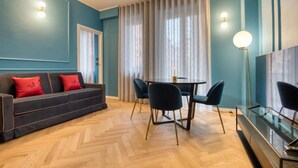 A modern living room with a sofa, dining table, chairs, and a TV. - VivimiHome-Suite Topazio, Luxury Apartment (Milan)