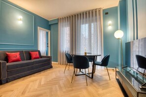 A modern living room with a sofa, dining table, chairs, and a TV. - VivimiHome-Suite Topazio, Luxury Apartment (Milan)