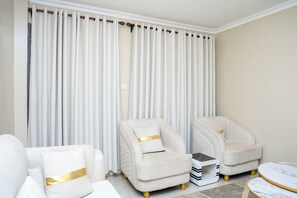 Ein Zimmer mit zwei Sesseln, einem kleinen Beistelltisch und einem Marmortisch.