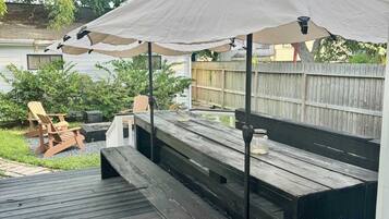 Una terraza de madera con bancos y una sombrilla.