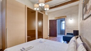 A bedroom with a bed, a wardrobe, a desk with a chair, and a view of a balcony. - 3BR Townhouse with Private Pool & BBQ in Birkirkara (Birkirkara)
