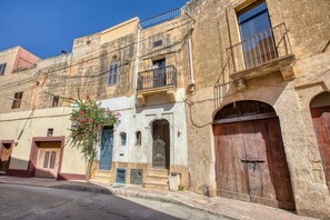 A traditional building with a wooden door, a balcony with metal railings, and a small window. - 3BR Townhouse with Private Pool & BBQ in Birkirkara (Birkirkara)