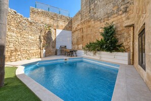 Ein Swimmingpool mit Steinmauern und einer Grillgelegenheit.