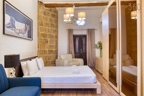 Un dormitorio con cama, una silla, cómoda y espejo.