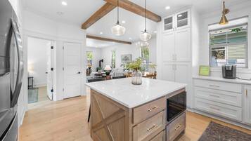 Une cuisine moderne dotée d’un grand îlot central, de meubles en bois et de luminaires suspendus.