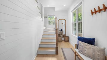 Una escalera de madera con barandilla que conduce a un rellano con un banco y un espejo.