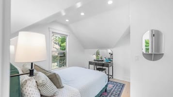 A bedroom with a bed, a desk, a chair, a lamp, a window, and a mirror.