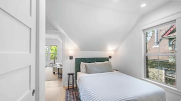 A bedroom with a bed, bedside lamps, a window, and a view of the outside.