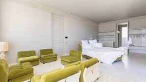 A modern bedroom with a large bed, a seating area with green chairs, and a walk-in closet with hanging space. - Fresnaye Villa, Moroccan Escape & Two Pools (Cape Town)