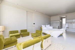 A modern bedroom with a large bed, a seating area with green chairs, and a walk-in closet with hanging space. - Fresnaye Villa, Moroccan Escape & Two Pools (Cape Town)