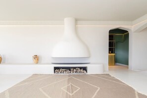 A modern interior with a white fireplace, a patterned rug, and a minimalist design. - Fresnaye Villa, Moroccan Escape & Two Pools (Cape Town)
