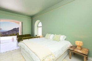 Une chambre avec un grand lit, une vue sur la ville et un balcon.