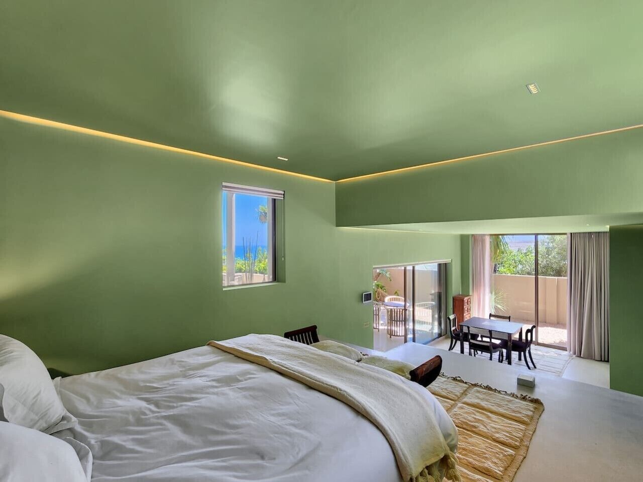 Une chambre avec un grand lit, un coin repas avec une table et des chaises, et une vue sur l’extérieur grâce à une porte coulissante.