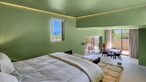 A bedroom with a large bed, a dining area with a table and chairs, and a view of the outdoors through a sliding door. - Fresnaye Villa, Moroccan Escape & Two Pools (Cape Town)