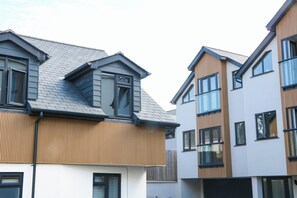 Ein modernes Wohngebäude mit geneigtem Dach, großen Fenstern und einer Kombination aus Holz- und weißer Fassade.