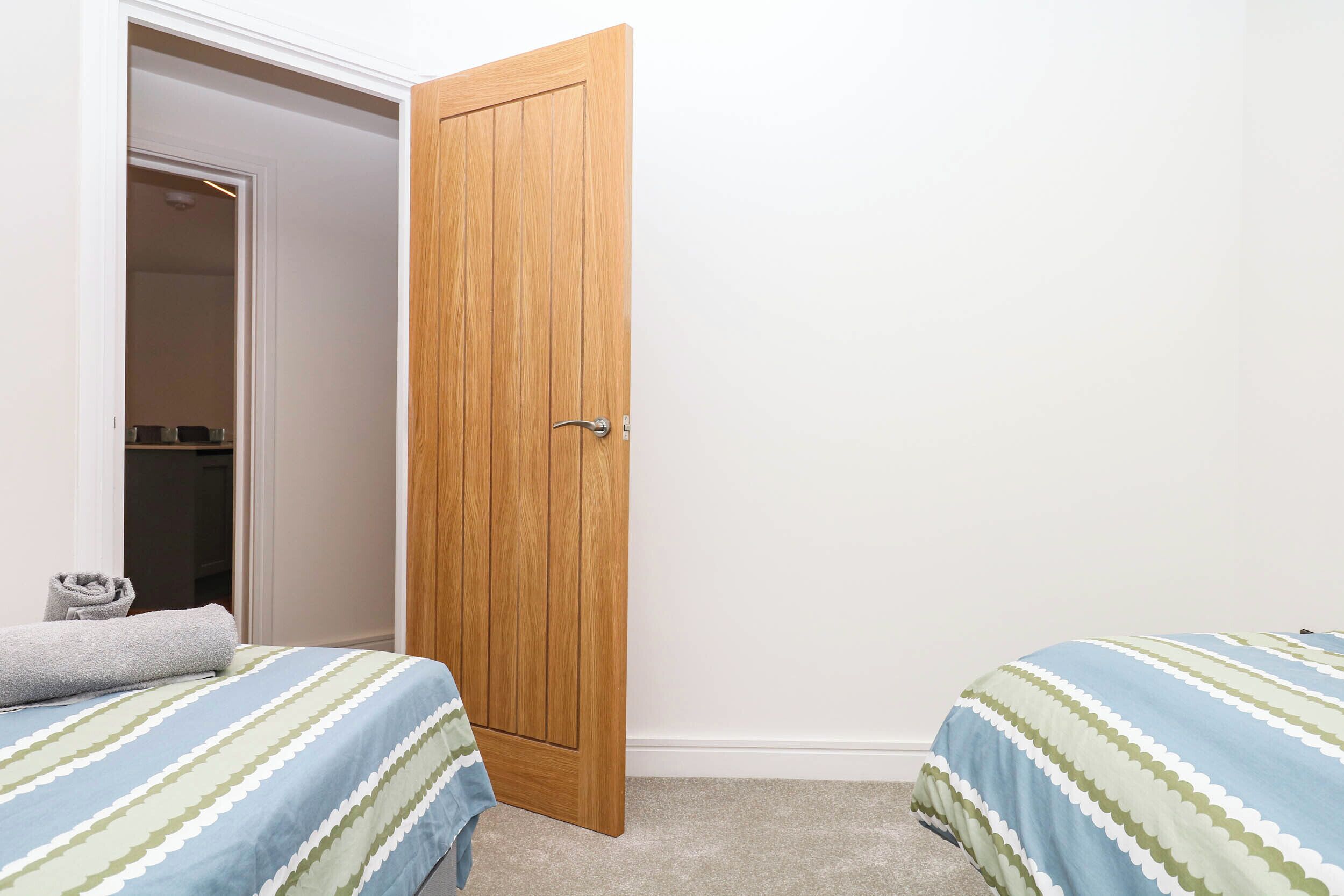 Un dormitorio con dos camas, una puerta de madera y un armario.
