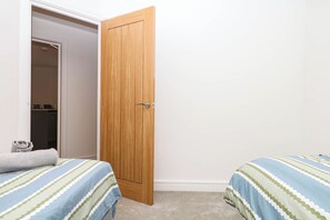 Ein Schlafzimmer mit zwei Betten, einer Holztür und einem Kleiderschrank.