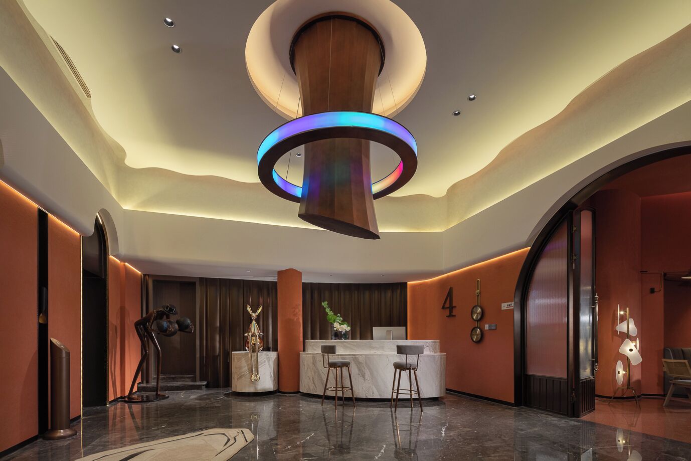 Eine moderne Lobby mit einer zentralen Rezeption, Marmorböden und einer markanten, runden Leuchte.
