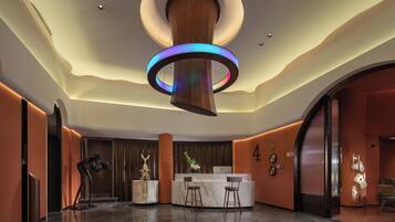Eine moderne Lobby mit einer zentralen Rezeption, Marmorböden und einer markanten, runden Leuchte.