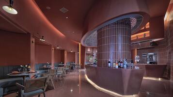 Un interior de restaurante moderno con cabinas, una zona de bar curva y una columna central.