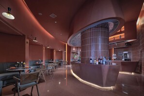 Interior de restaurante moderno com cabines, área de bar curva e uma coluna central.