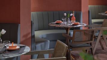 Un interior de restaurante con cabinas, mesas redondas y sillas de mimbre.