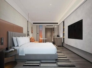 Una habitación de hotel moderna con una cama grande, mesitas de noche, un escritorio y una televisión.