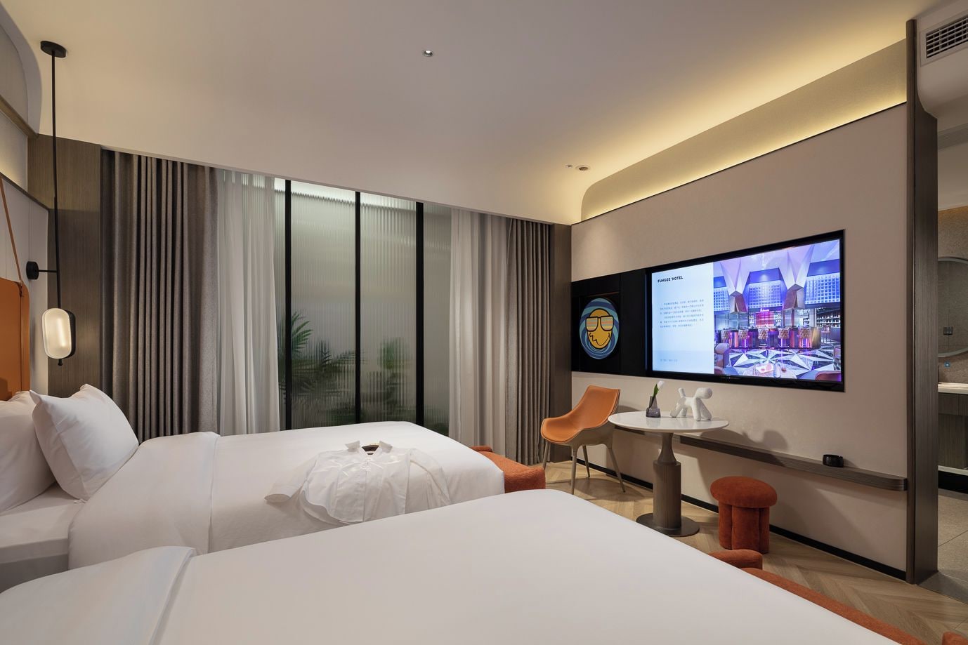 A hotel room with two beds, a TV, a small table, and a chair.