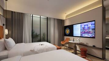 A hotel room with two beds, a TV, a small table, and a chair.