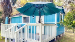 A blue house with a white deck, a large umbrella, and a small tree in the background. - The Blue Sunshine Retreat (Citra)
