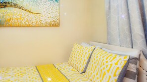 A room with a bed, a painting on the wall, and a window with curtains. - The Blue Sunshine Retreat (Citra)