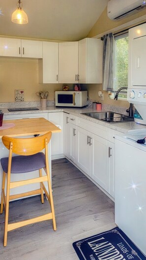 Una cucina con mobili bianchi, un tavolo di legno, un forno a microonde e un lavandino.