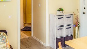 A room with a dining table, chairs, a cabinet with drawers, and a door leading to another room. - The Blue Sunshine Retreat (Citra)
