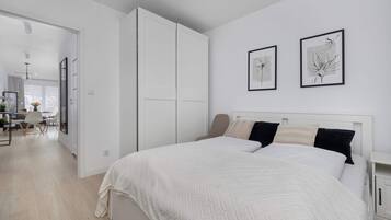 A bedroom with a bed, a wardrobe, and two framed artworks on the wall.