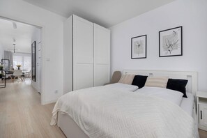 Ein Schlafzimmer mit einem Bett, einem Kleiderschrank und zwei gerahmten Kunstwerken an der Wand.