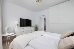 Ein modernes Schlafzimmer mit Bett, Fernseher, Schreibtisch und Kleiderschrank.