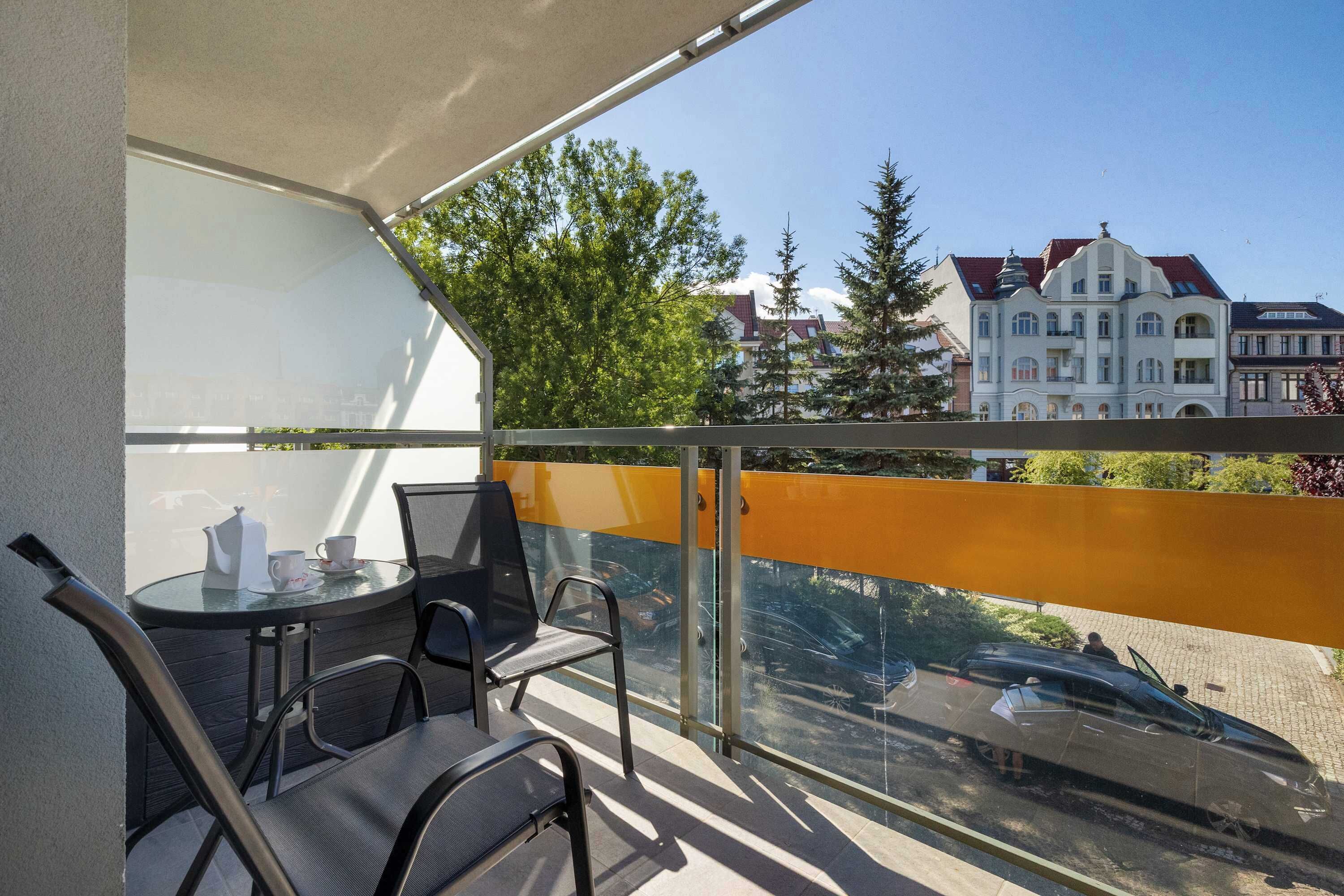 Ein Balkon mit Tisch und Stühlen, Blick auf Gebäude und eine Straße mit Autos.
