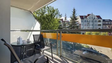 Ein Balkon mit Tisch und Stühlen, Blick auf Gebäude und eine Straße mit Autos.
