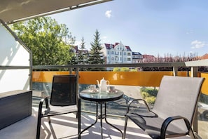 Ein Balkon mit Tisch und Stühlen, Blick auf Gebäude und wolkenloser Himmel.