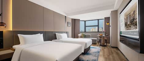 A hotel room with two beds, a desk, a chair, a TV, and a large window with a city view.