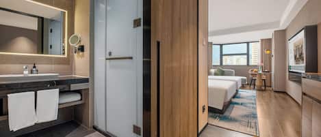 Una habitación de hotel moderna con baño, cama, una mesita y vistas a la ciudad.