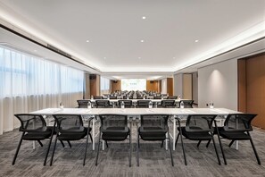 Une salle de conférence avec une longue table, des chaises et un écran de projection à l’avant.