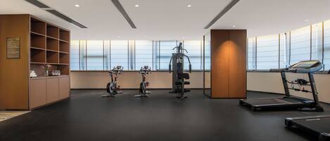 Et moderne fitnesscenter med træningsudstyr, løbebånd og en vægmonteret cykel.