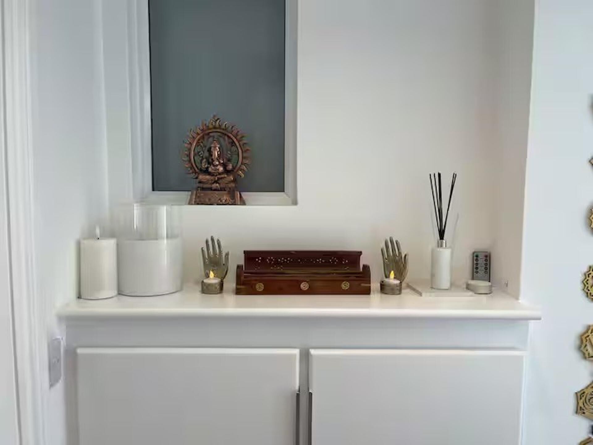 A white console table with a framed religious icon, candles, a small statue, and a decorative box.