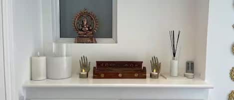 A white console table with a framed religious icon, candles, a small statue, and a decorative box.