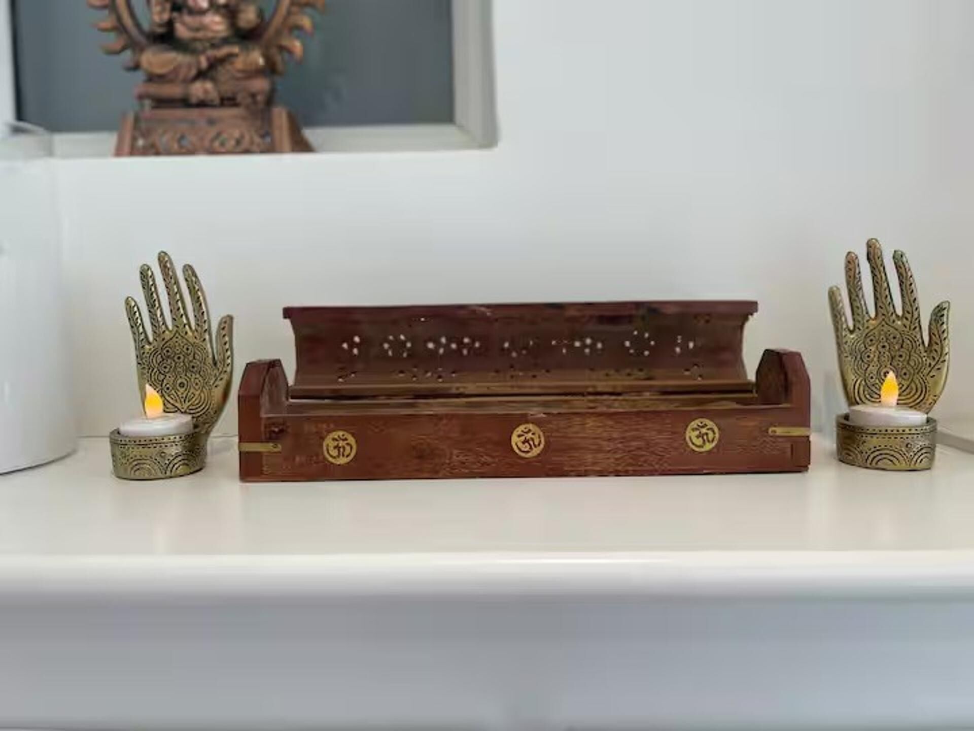 A wooden tray with a candle holder on each end, placed on a white shelf.