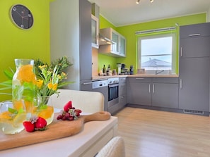 A modern kitchen with grey cabinets, a window, and a view of a house. - Hot Tub & View of the Dolomites on the Eifelsteig Trail (Gerolstein)